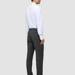 A person seen from behind wears a white button-down shirt, Motion Suit Pants Regular Pepper Grey, and black loafers.