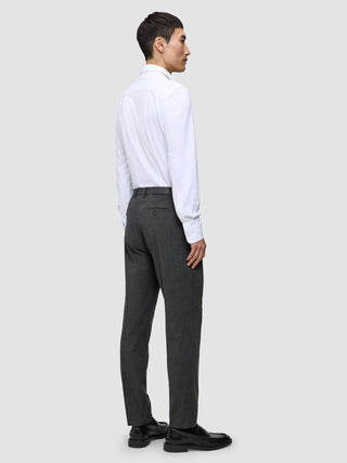 A person seen from behind wears a white button-down shirt, Motion Suit Pants Regular Pepper Grey, and black loafers.