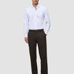 A man wears a white button-down shirt with a relaxed fit, Motion Suit Pants Relaxed Cognac, and dark loafers.