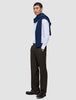 A man wearing a white pinstriped button-down shirt, a navy blue sweater draped over his shoulders, loafers, and Motion Suit Pants Relaxed Cognac.