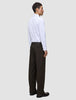 A man viewed from behind wears a white button-down shirt, Motion Suit Pants Relaxed Cognac, and dark brown loafers.