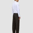 A man viewed from behind wears a white button-down shirt, Motion Suit Pants Relaxed Cognac, and dark brown loafers.
