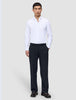 A man wearing a white button-down shirt and Motion Suit Pants Relaxed Midnight Blue, standing with one hand in his pocket.