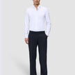 A man wearing a white button-down shirt and Motion Suit Pants Relaxed Midnight Blue, standing with one hand in his pocket.