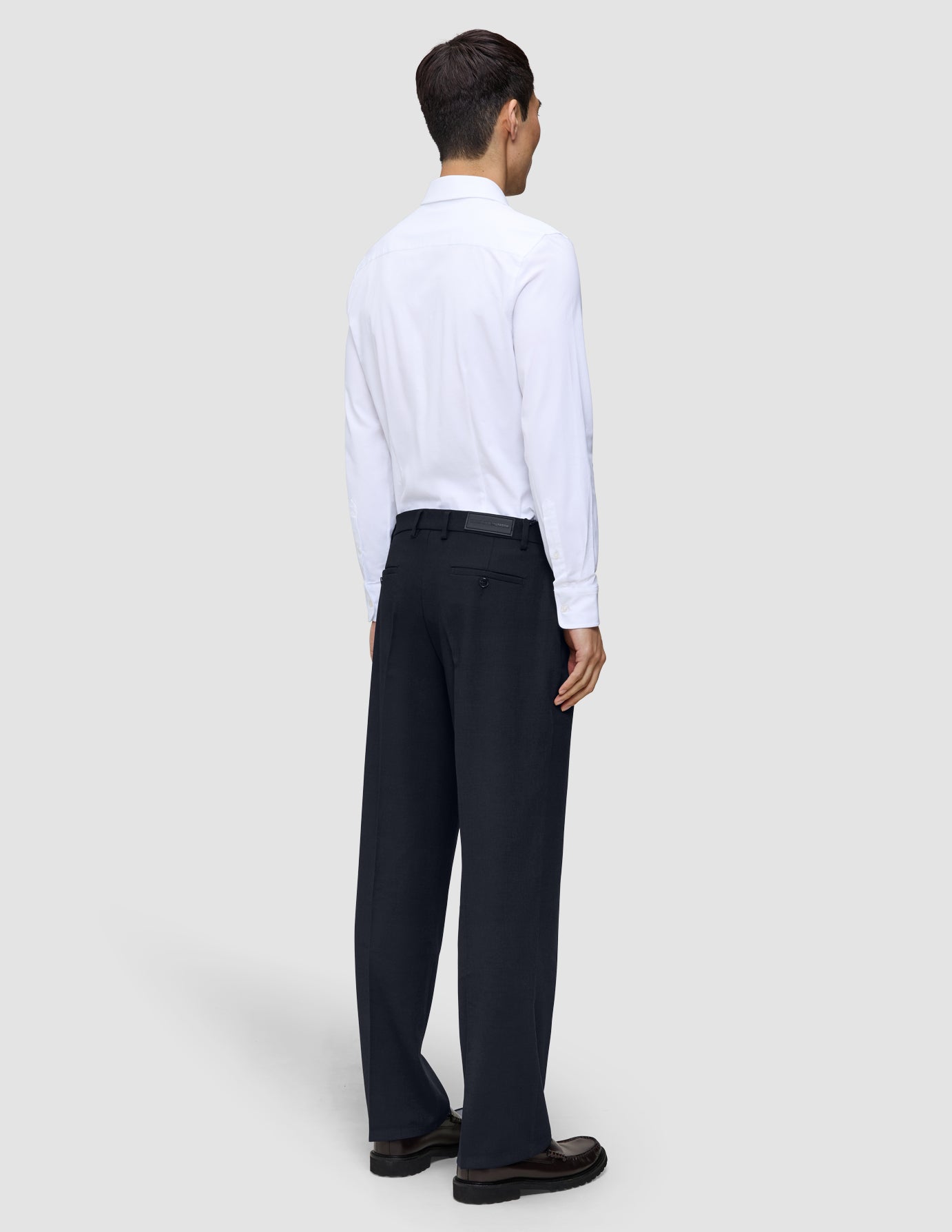 A person seen from behind wearing a white button-down shirt and Midnight Blue Motion Suit Pants Relaxed.