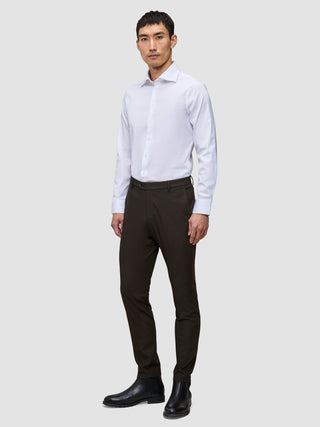 A man wearing a white dress shirt, Motion Suit Pants Slim Cognac, and black leather boots.