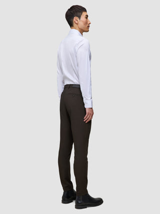 A man in profile wears a white dress shirt, slim-fit Motion Suit Pants Slim Cognac, and black leather boots.
