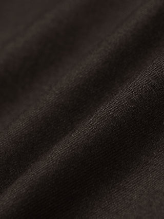Close-up view of dark brown, 360° stretch fabric with subtle folds on the Motion Suit Pants Slim Cognac.