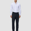 A man wears a white button-down shirt, Motion Suit Pants Slim Midnight Blue, and brown loafers.