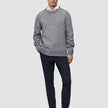 A man wearing a grey crew-neck sweater over a white collared shirt, paired with Motion Suit Pants Slim Midnight Blue and dark brown loafers.