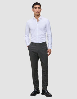 A man wearing a white button-down shirt, Motion Suit Pants Slim Pepper Grey, and black loafers.