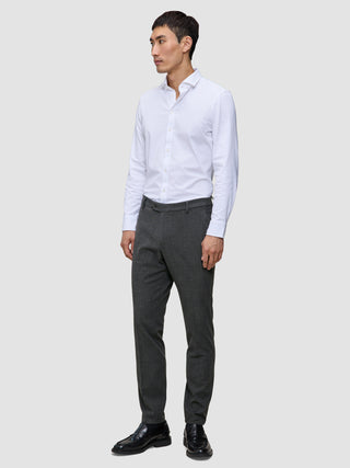 A man wearing a white button-down shirt, Motion Suit Pants Slim Pepper Grey, and black dress shoes.