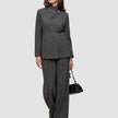A person wearing The suit with a statement, featuring a classic check high-neck Nara Blazer and wide-leg trousers, carrying a black handbag.
