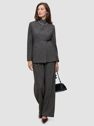 A person wearing The suit with a statement, featuring a classic check high-neck Nara Blazer and wide-leg trousers, carrying a black handbag.