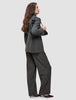 A person wearing The suit with a statement in a classic check pattern, featuring a Nara Blazer and wide-leg pants, while carrying a black shoulder bag.