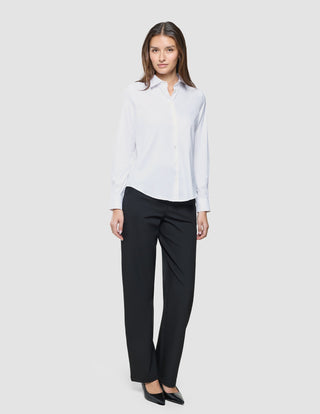 A woman stands wearing a Women Oxford Shirt White Regular and black trousers.