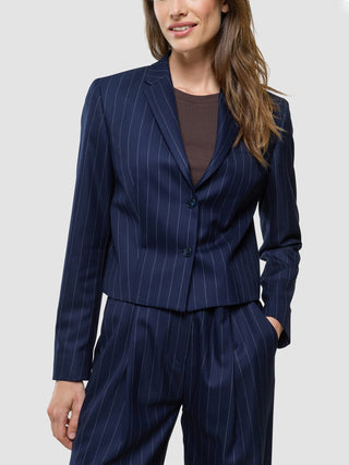 A smiling woman wearing a Women Raina Short Blazer Night Sky Pinstripe over a brown top.