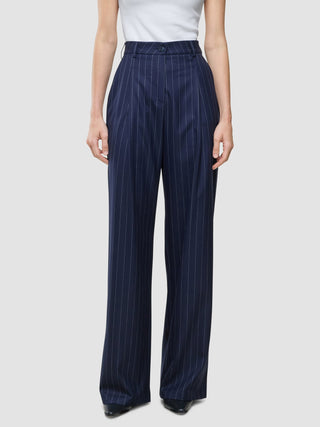 A person wearing Women Raina Pants Wide Night Sky Pinstripe paired with a white sleeveless top, embodying a minimalist Scandinavian design.