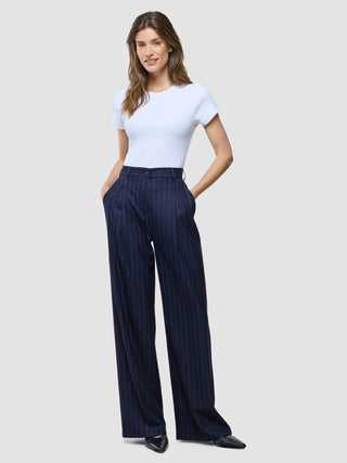 A woman wearing a white crew-neck t-shirt and Women Raina Pants Wide Night Sky Pinstripe.