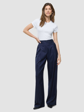 A woman wearing a white short-sleeved t-shirt and Women Raina Pants Wide Night Sky Pinstripe.
