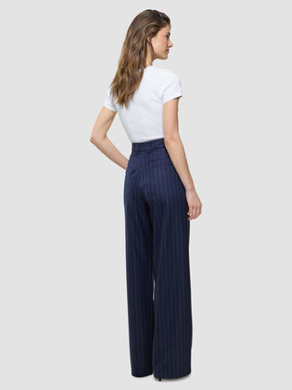 A woman wears a white t-shirt tucked into Women Raina Pants Wide Night Sky Pinstripe that embody Scandinavian design.