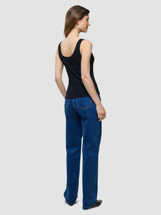 A woman seen from behind, wearing a Rib Tank Top Black paired with blue jeans.