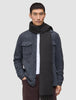 A man wears a Scarf Charcoal Grey with fringe ends over a white button-down shirt and a grey wool shirt jacket in a minimalist Scandinavian design.