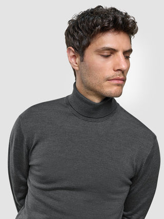 A man wearing a Seamless Premium Merino Knit Turtleneck Charcoal Grey looking toward the side.