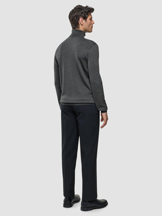 A man seen from behind wearing a Seamless Premium Merino Knit Turtleneck Charcoal Grey and dark trousers.