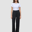A person wearing a white t-shirt and black Serene Pants Wide Black, featuring a high-waisted, wide-leg Scandinavian design.