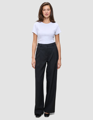 A person wearing a white t-shirt and black Serene Pants Wide Black, featuring a high-waisted, wide-leg Scandinavian design.