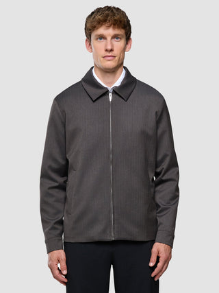 A man wearing a Siena Jacket Herringbone Dark Brown over a white collared shirt, featuring a lightweight fabric and Scandinavian design.