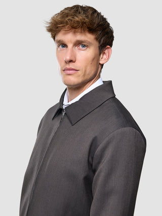 A man wearing a Siena Jacket Herringbone Dark Brown over a white collared shirt.