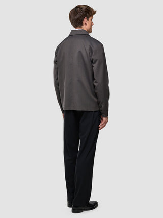A man seen from behind wearing a Siena Jacket Herringbone Dark Brown and black trousers, showcasing a clean Scandinavian design.