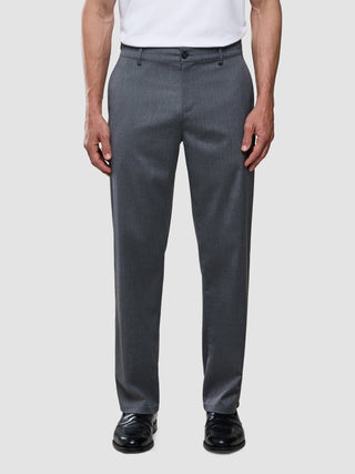 A man wearing a white t-shirt, Siena Pants Relaxed Fit Herringbone Grey, and black dress shoes.