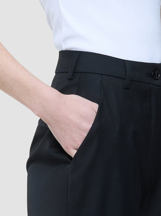 A person’s hand resting in the pocket of Women Skye Pants Tapered Black.