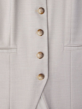 A close-up of the Women’s Skye Long Vest Sandy Beige Melange featuring four round, marbled buttons on light-colored fabric.