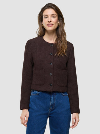 A woman wearing a Women Sorae Short Jacket Espresso and blue jeans.