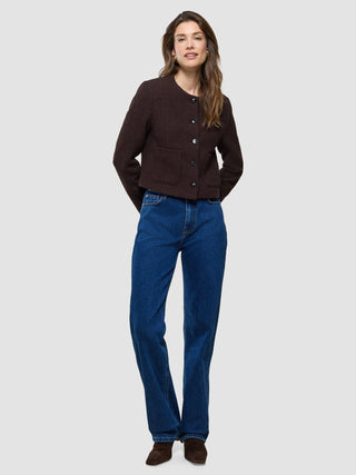 A woman wearing a Women Sorae Short Jacket Espresso and blue jeans.