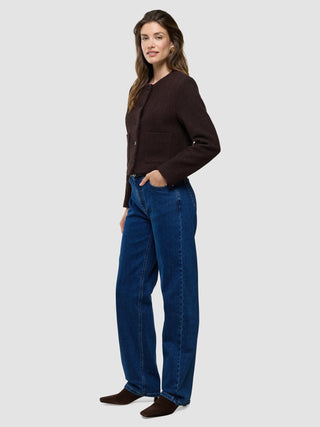 A woman wearing a Women Sorae Short Jacket Espresso and blue jeans.