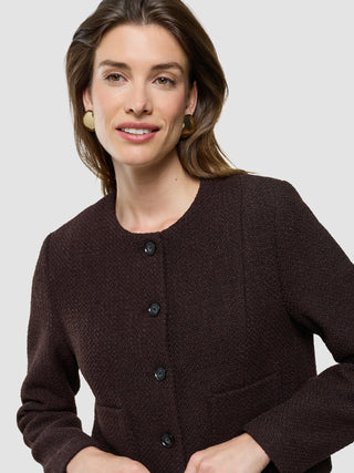 A woman wearing a Women Sorae Short Jacket Espresso and round gold earrings.