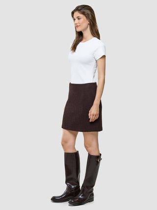 A woman wearing a white t-shirt, a Women Sorae Short Skirt Espresso, and dark brown knee-high boots.