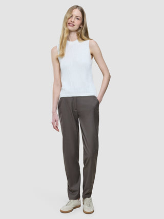 A woman wears a Women’s Structured Knit Top Off White, grey trousers, and white sneakers with brown soles.