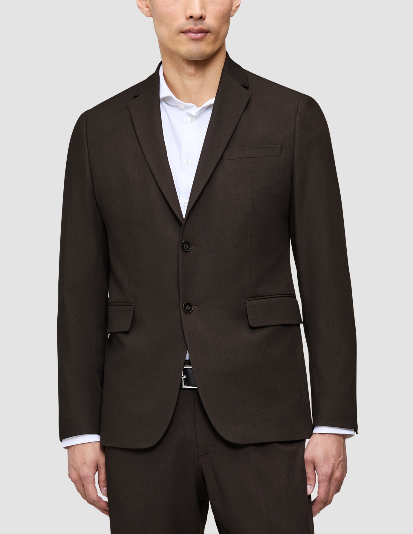 A person wearing a dark brown Motion Suit jacket from The suit that does it all over a crisp, elevated white button-down shirt.