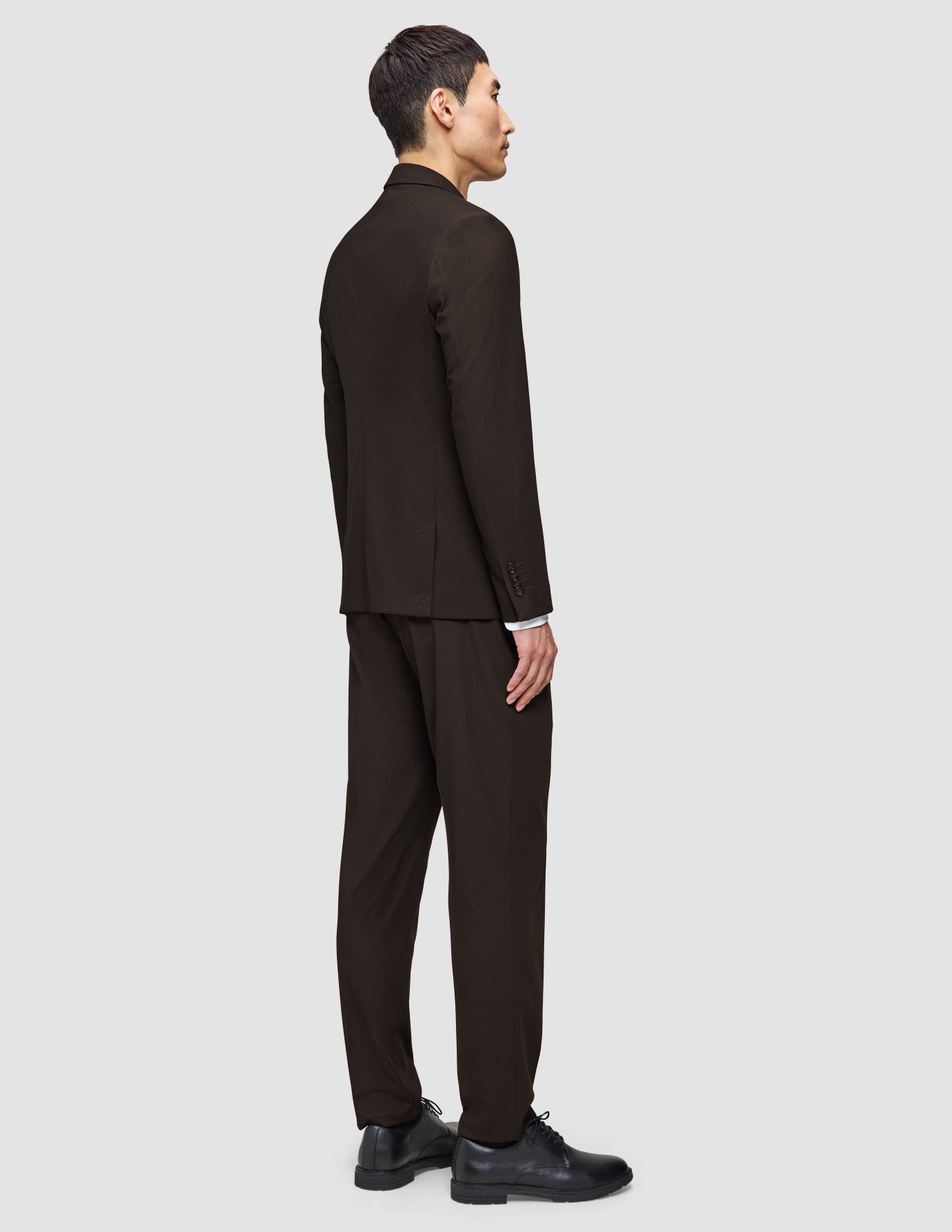 A person from the back wearing The suit that does it all in dark brown with a white Elevated Shirt and black shoes for a classic polished look.