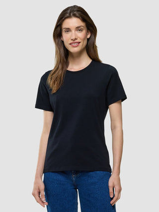 A woman wearing a Supima T-shirt Black and 360° stretch blue jeans.