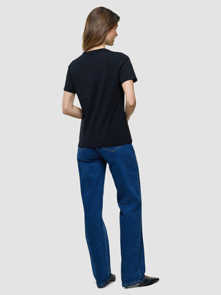 A woman seen from behind wearing a Supima T-shirt Black and blue jeans.