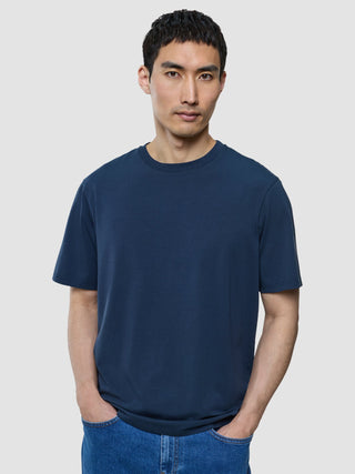 A man wearing a Supima T-shirt Box Fit Navy and blue jeans featuring 360° stretch.