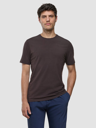 A man wearing a Supima T-shirt Deep Brown and blue trousers with 360° stretch.