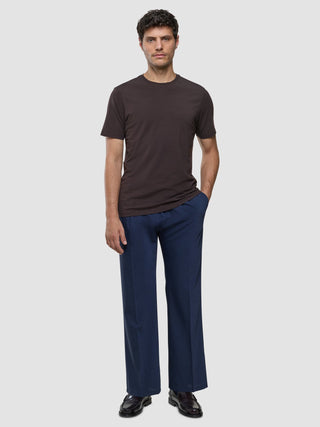 A man wearing a Supima T-shirt Deep Brown, blue trousers, and dark loafers featuring 360° stretch.